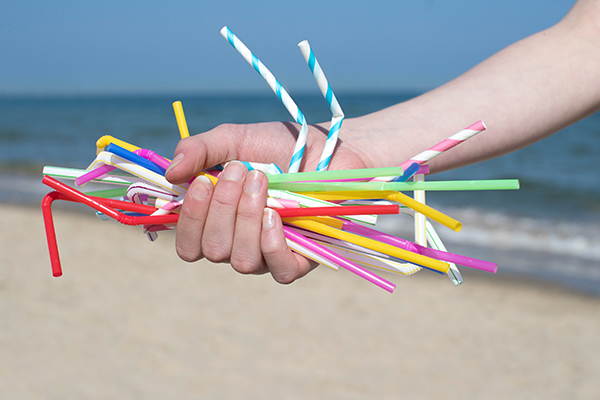 Hand holding straws on a beach